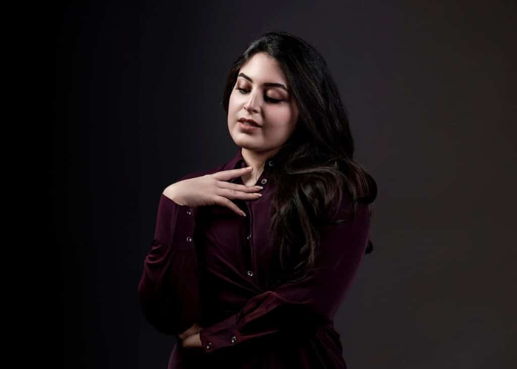 Female model portrait captured in low-key studio lighting with elegant pose for fashion photography